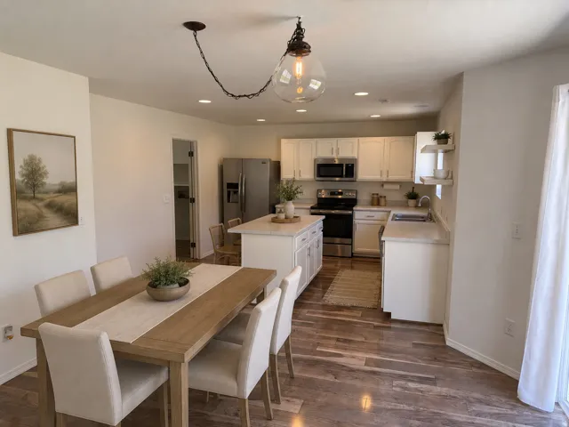 Open-concept kitchen and dining area featuring wood-finish flooring, white cabinetry, a kitchen island, and recessed lighting