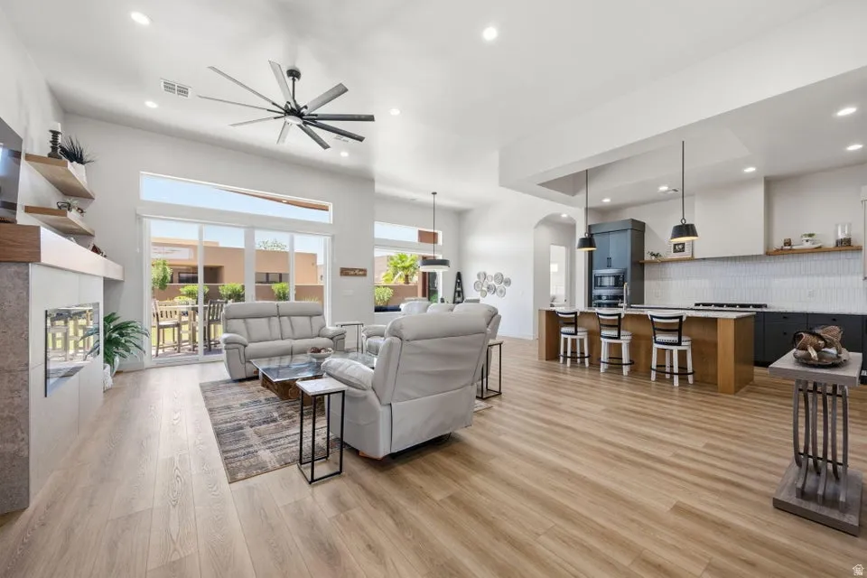 Open-concept living space featuring wood-finish flooring, a modern fireplace with integrated shelving, and large sliding glass doors