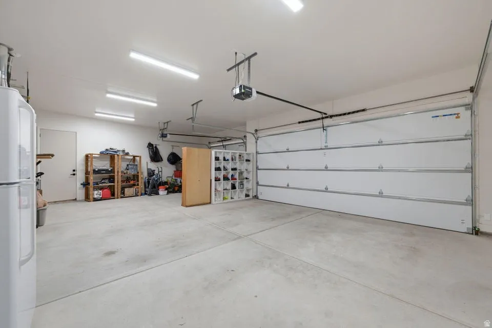 Spacious garage featuring a concrete floor, bright overhead lighting, and two sectional garage doors with openers