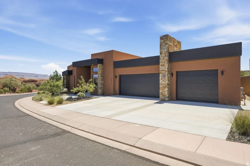 Contemporary exterior featuring a stucco finish, stone accents, and dark trim