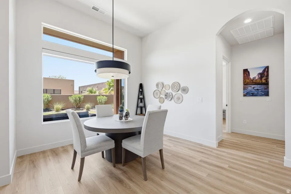 Dining area featuring a large picture window, wood-finish flooring, and a contemporary pendant light fixture