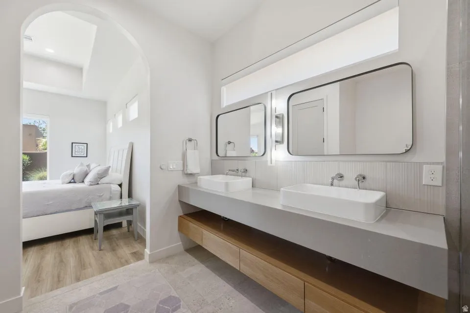 Bathroom featuring a dual vanity with rectangular vessel sinks, wall-mounted faucets, and framed mirrors