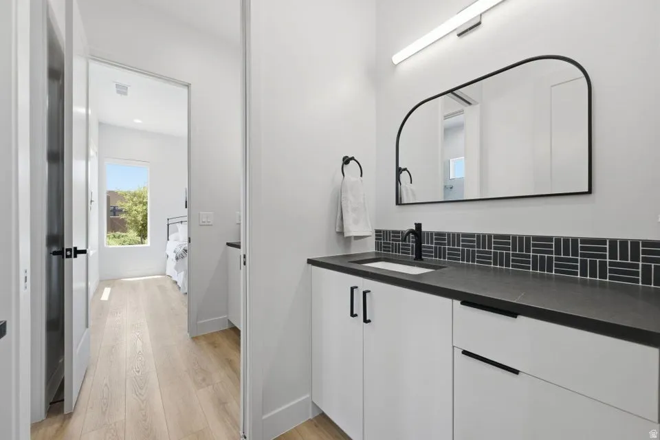 Modern vanity with a dark countertop, integrated sink, and matte black faucet