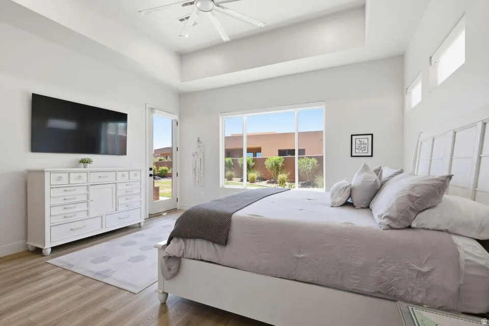 Room featuring a tray ceiling, ceiling fan, and wood-finish flooring