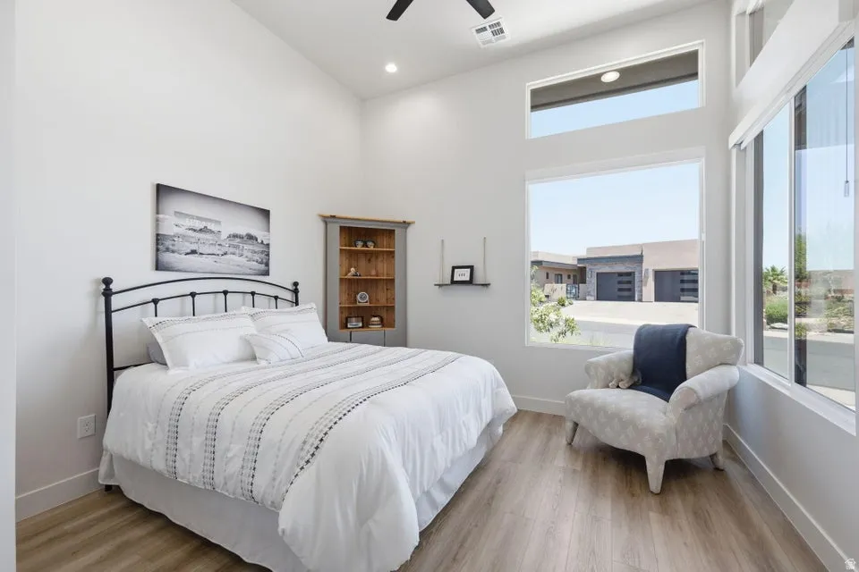 Bedroom featuring vaulted ceilings, wood-finish flooring, recessed lighting, and multiple windows including transoms