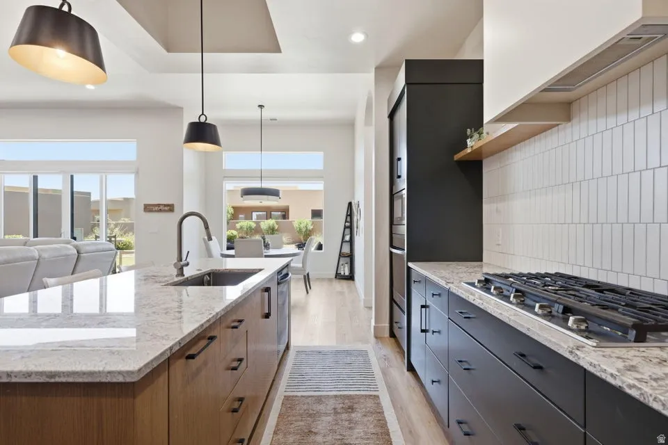 Gourmet kitchen featuring a gas range, built-in oven, light-toned countertops, contrasting cabinetry, and a subway tile backsplash