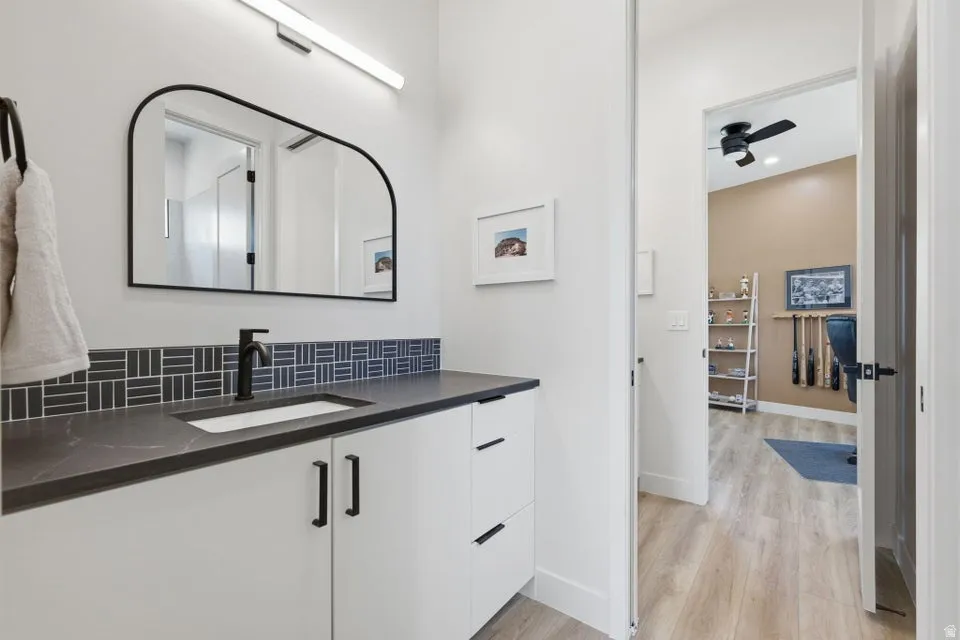 Modern bathroom vanity with white cabinetry, dark countertop, and integrated sink