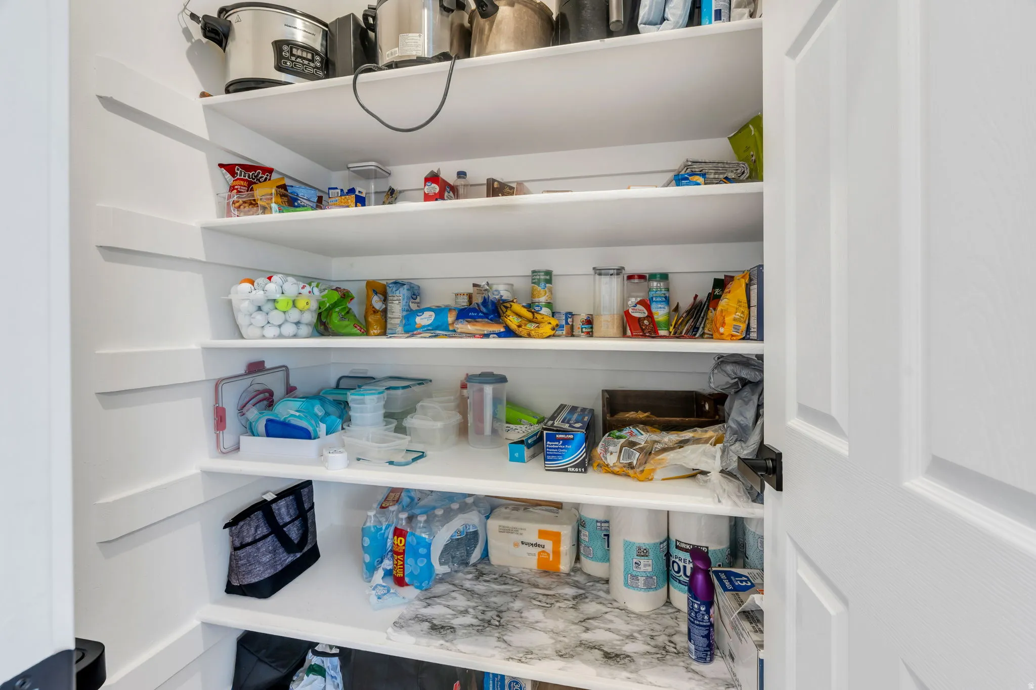 White built-in shelving providing ample storage, a paneled door, and dark hardware