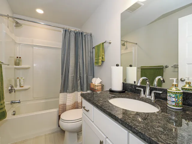 White vanity with an undermount sink and dark granite-style countertop