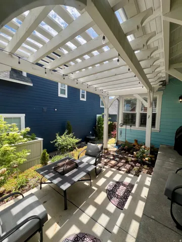 Expansive concrete patio featuring a white pergola with string lights