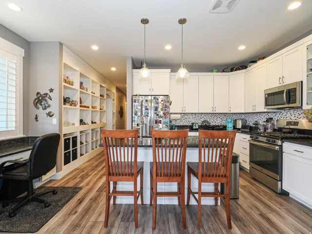Kitchen featuring white cabinetry, stainless steel appliances, granite countertops, and a patterned tile backsplash