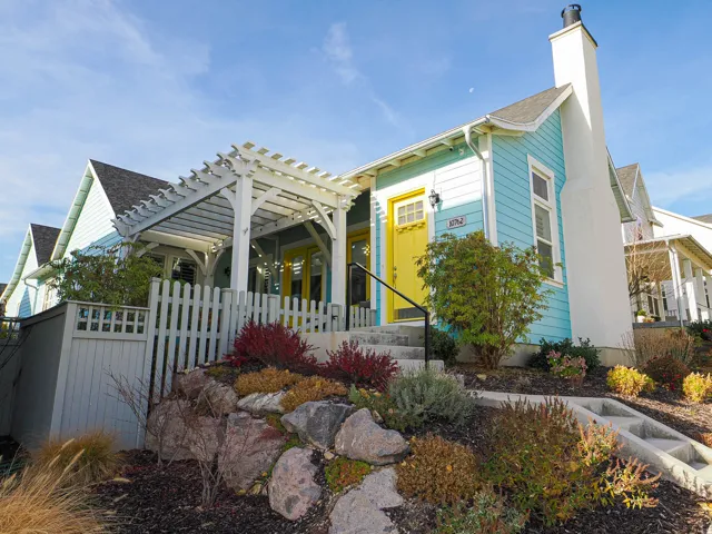 Vibrant exterior with horizontal siding, a bright yellow entry door, and a white pergola-covered patio