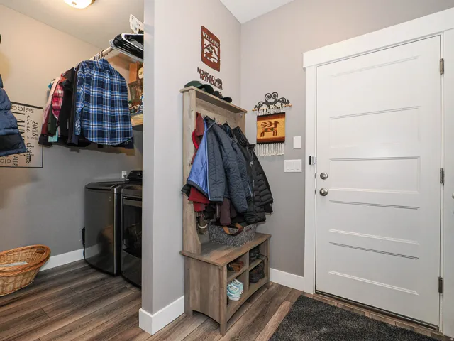 Laundry area with wood-finish flooring, built-in shelving, and a white paneled door
