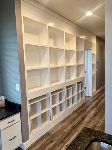 Built-in shelving with varied cubby sizes, recessed lighting, wood-finish flooring, and a countertop with an undermount sink