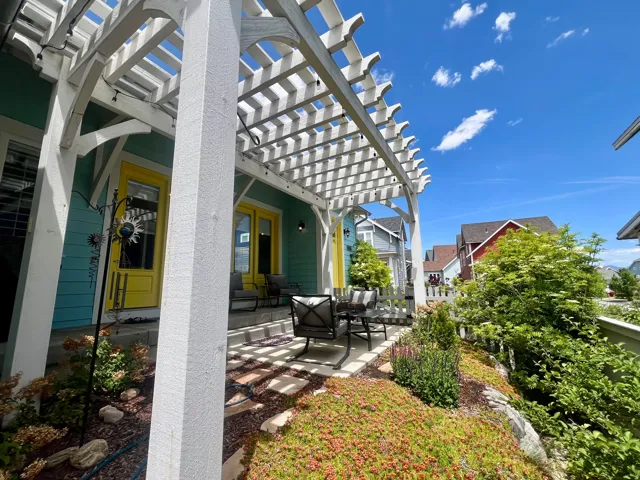 Inviting patio featuring a white pergola, string lighting, and vibrant landscaping