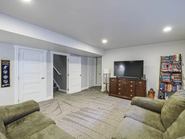 Recessed lighting illuminates the room, featuring a carpeted floor, white walls, and white paneled doors