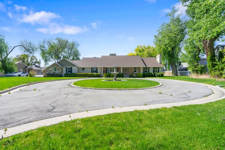Circular driveway leading to a stone and siding residence with a central fountain feature