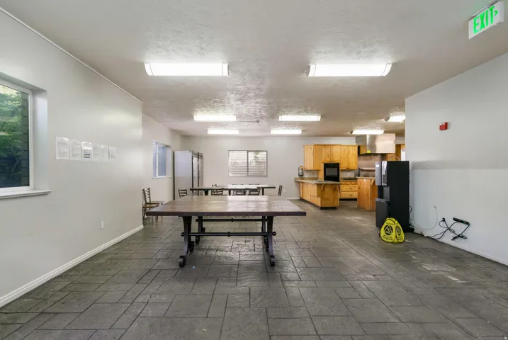 Spacious common area featuring stamped concrete flooring, a full kitchen with wood cabinetry and stainless steel appliances, multiple windows providing natural light, and ample room for gatherings
