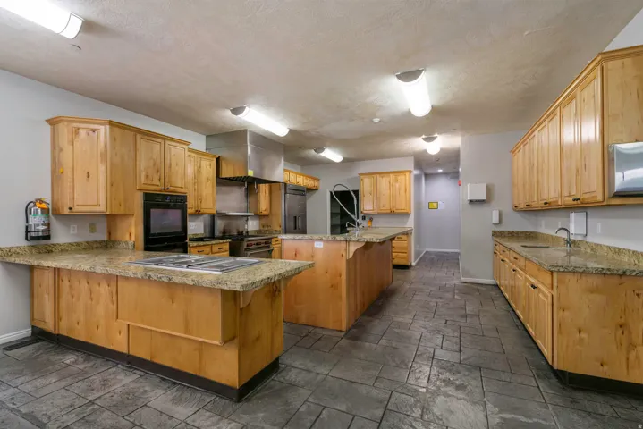 Spacious kitchen featuring multiple light wood-finish cabinetry banks with granite-style countertops