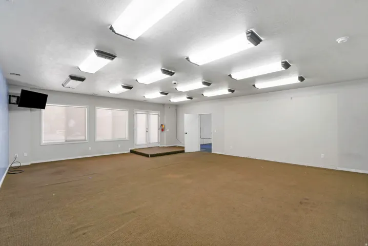 Spacious room featuring ample overhead fluorescent lighting, a built-in elevated platform, and wall-mounted television