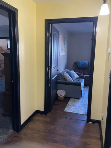 Entryway featuring wood-finish flooring, light yellow painted walls, and dark trim