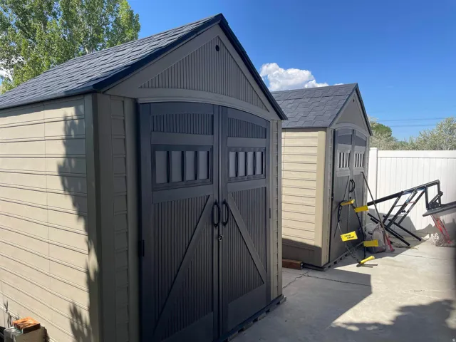 Two detached storage sheds featuring shingle-style roofing, durable composite siding, and dark-paneled double doors with black hardware
