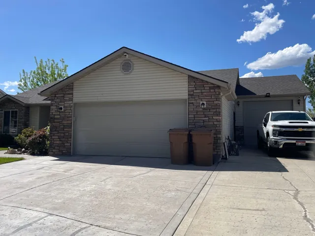 Front exterior featuring a stone and siding facade, a two-car garage, an additional single-car garage, and a concrete driveway