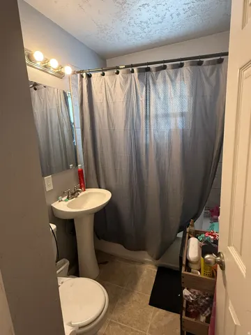 Bathroom with a pedestal sink, chrome faucet, and a wall-mounted mirror