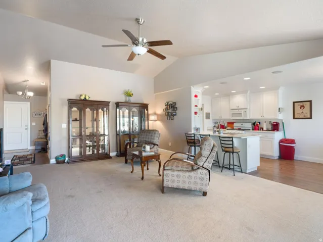 Open-concept living space featuring a vaulted ceiling with a ceiling fan, recessed lighting, and light neutral-toned walls