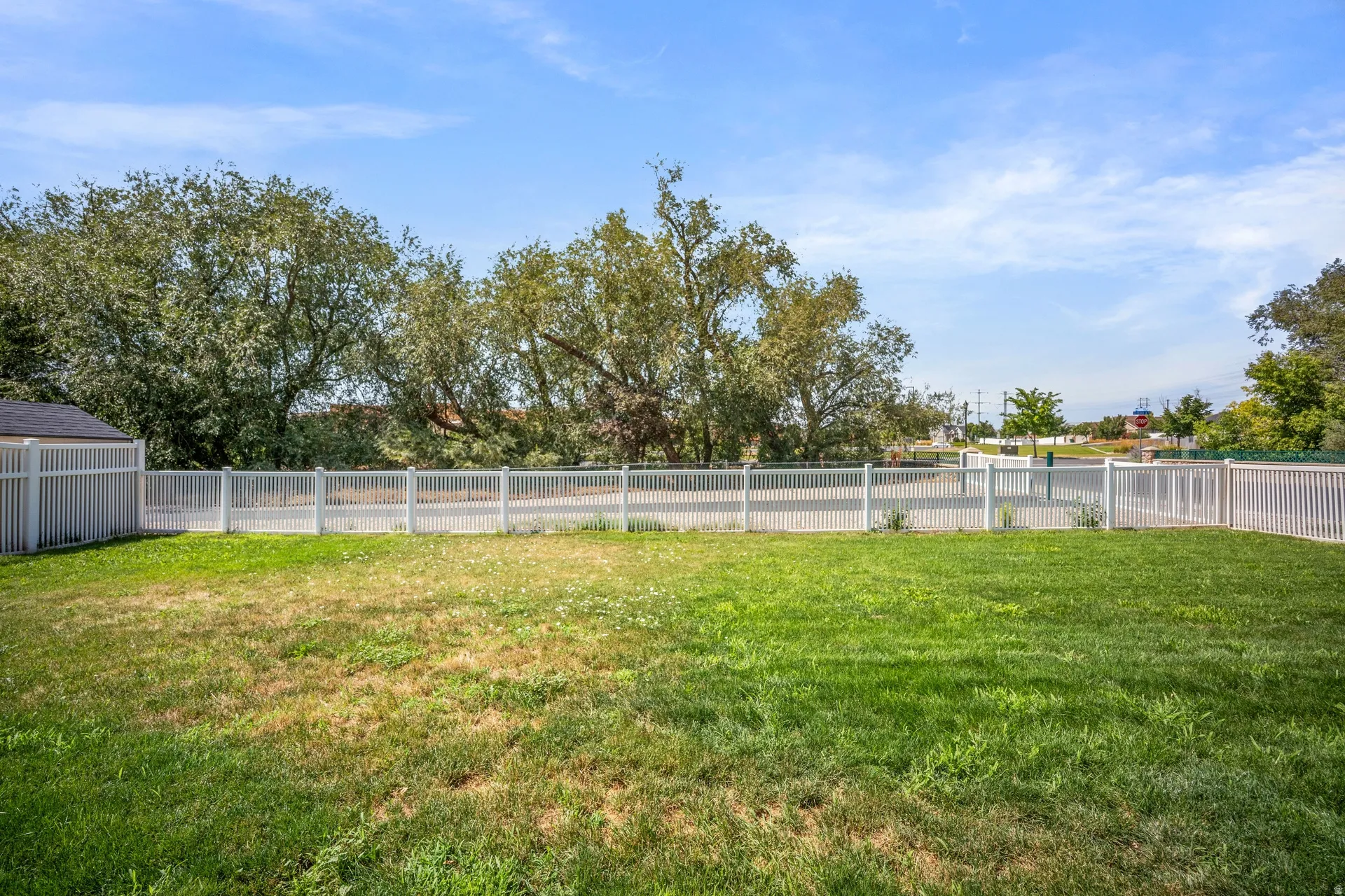 Expansive fenced yard with a manicured lawn and mature trees