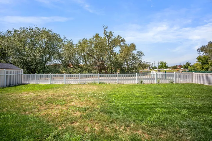 Expansive fenced yard with a manicured lawn and mature trees