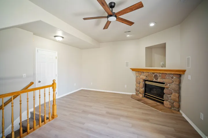 Stone-faced fireplace with a wood mantel, wood-finish flooring, and recessed ceiling lighting
