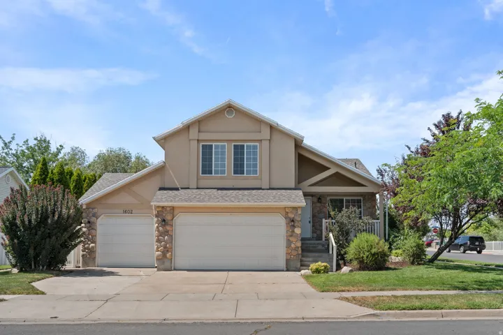 Stucco exterior with stone accents, two-car garage, and established landscaping