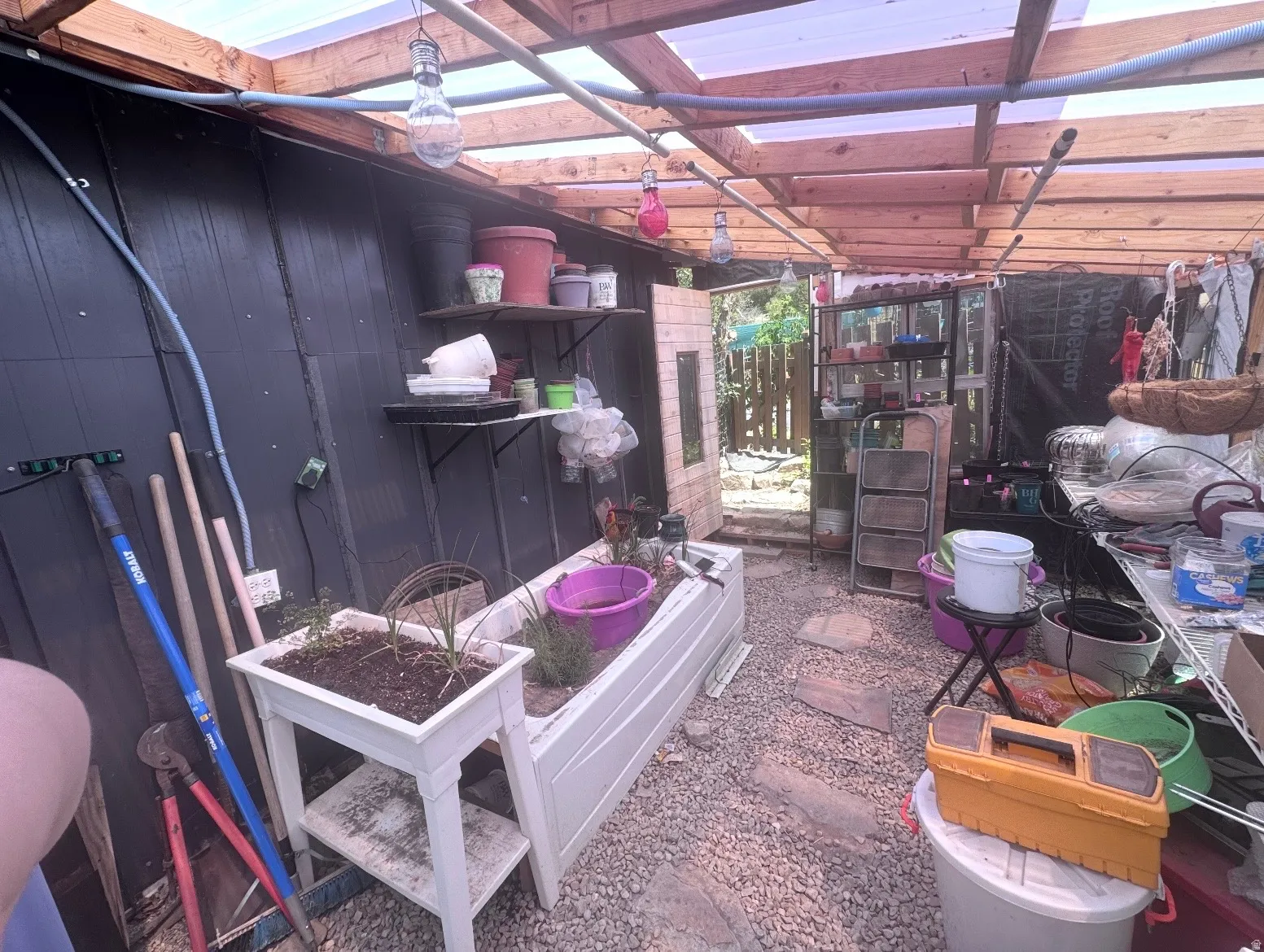 Greenhouse structure featuring a wood frame, translucent panel roof, and gravel flooring