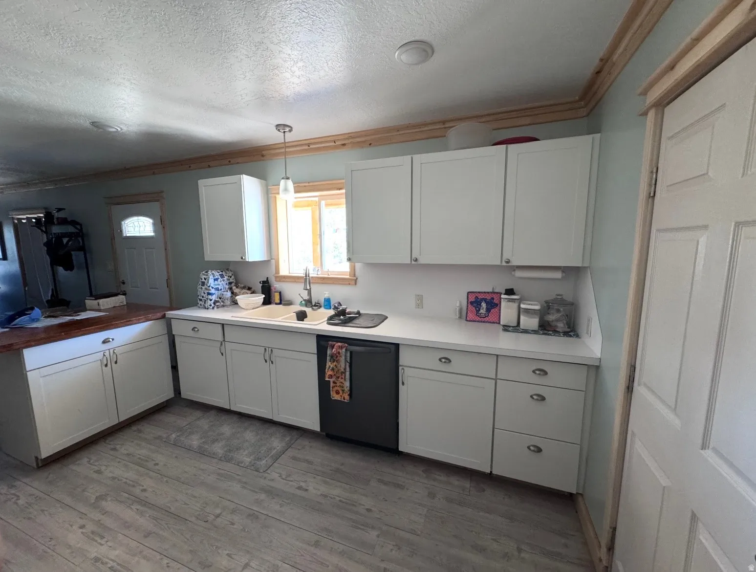 Kitchen featuring white cabinetry, light-colored countertops, and wood-finish flooring