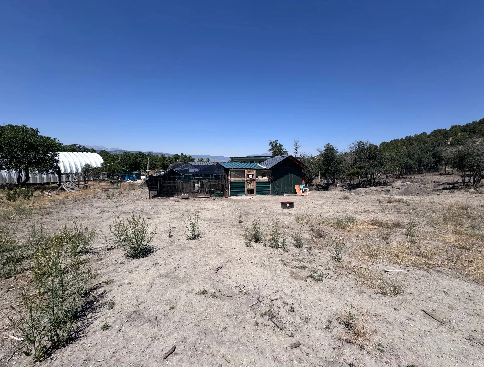 Expansive rural property featuring multiple outbuildings, including a primary residence with dark exterior trim and a corrugated metal structure