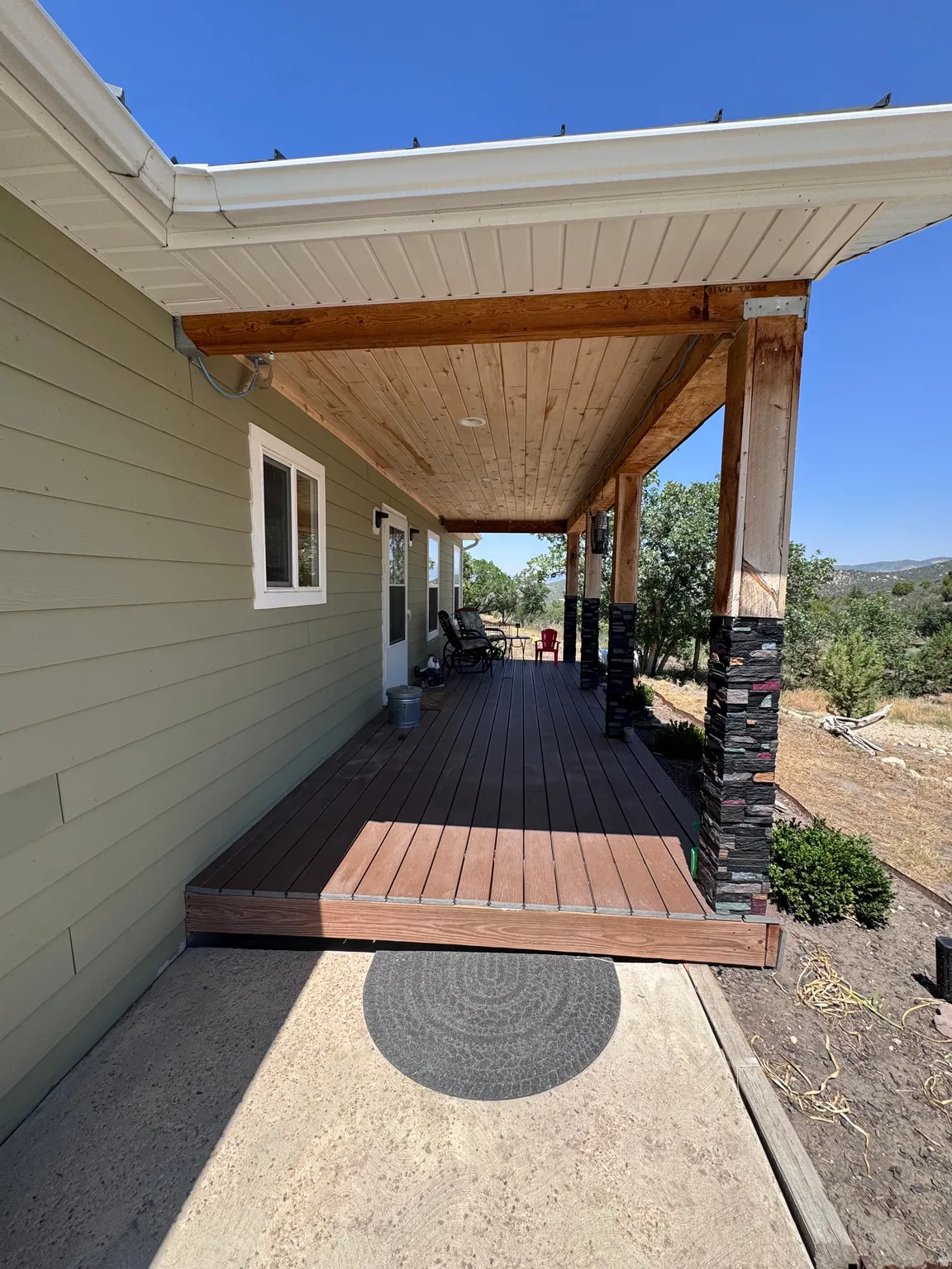 Covered patio featuring a composite deck with clean lines, wooden beam ceiling, and metal support posts