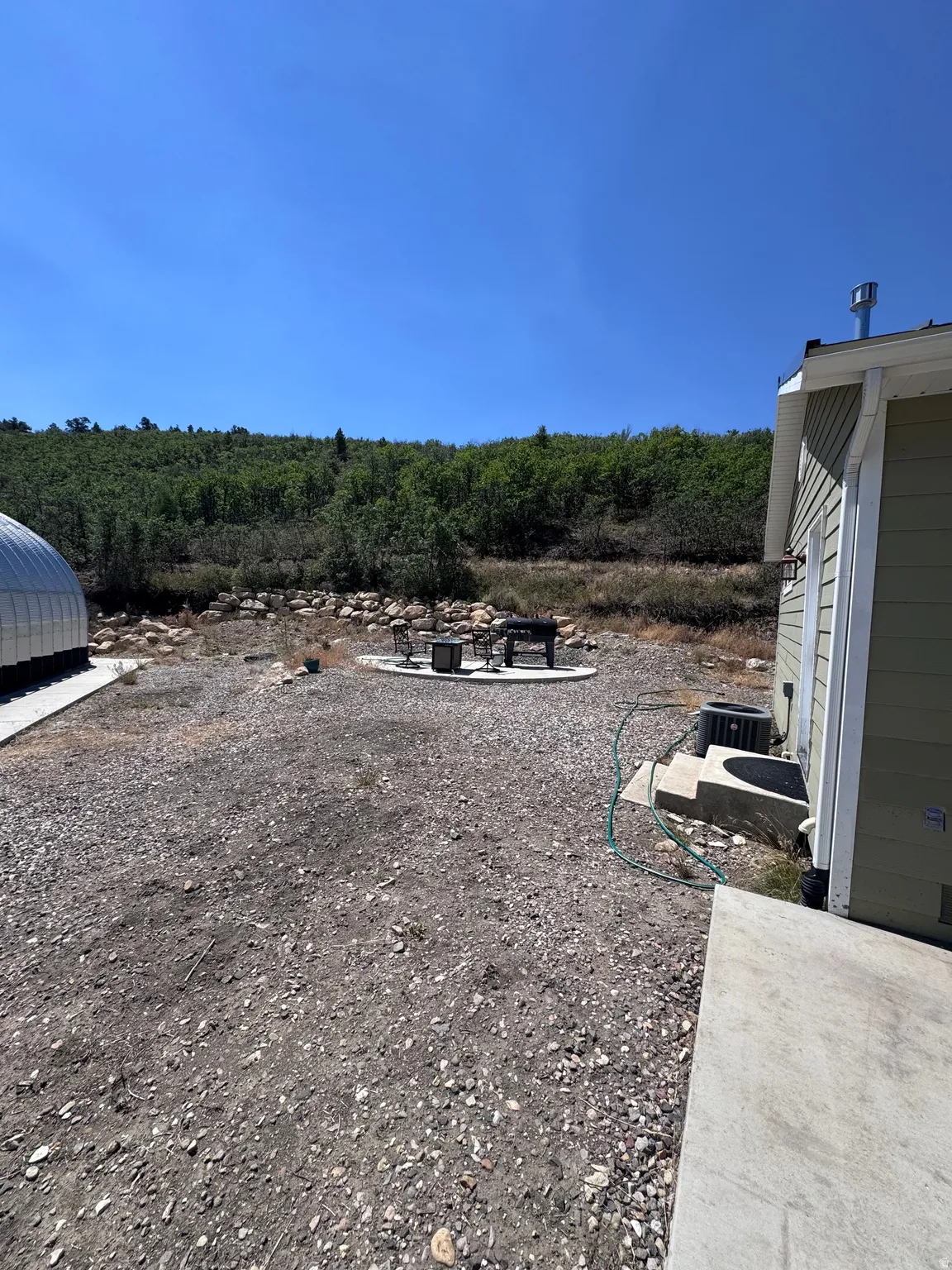 Expansive gravel yard with a circular patio featuring a fire pit