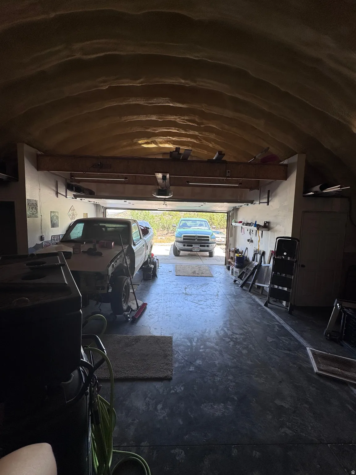 Spacious garage with arched ceiling and concrete flooring, offering ample storage and workspace