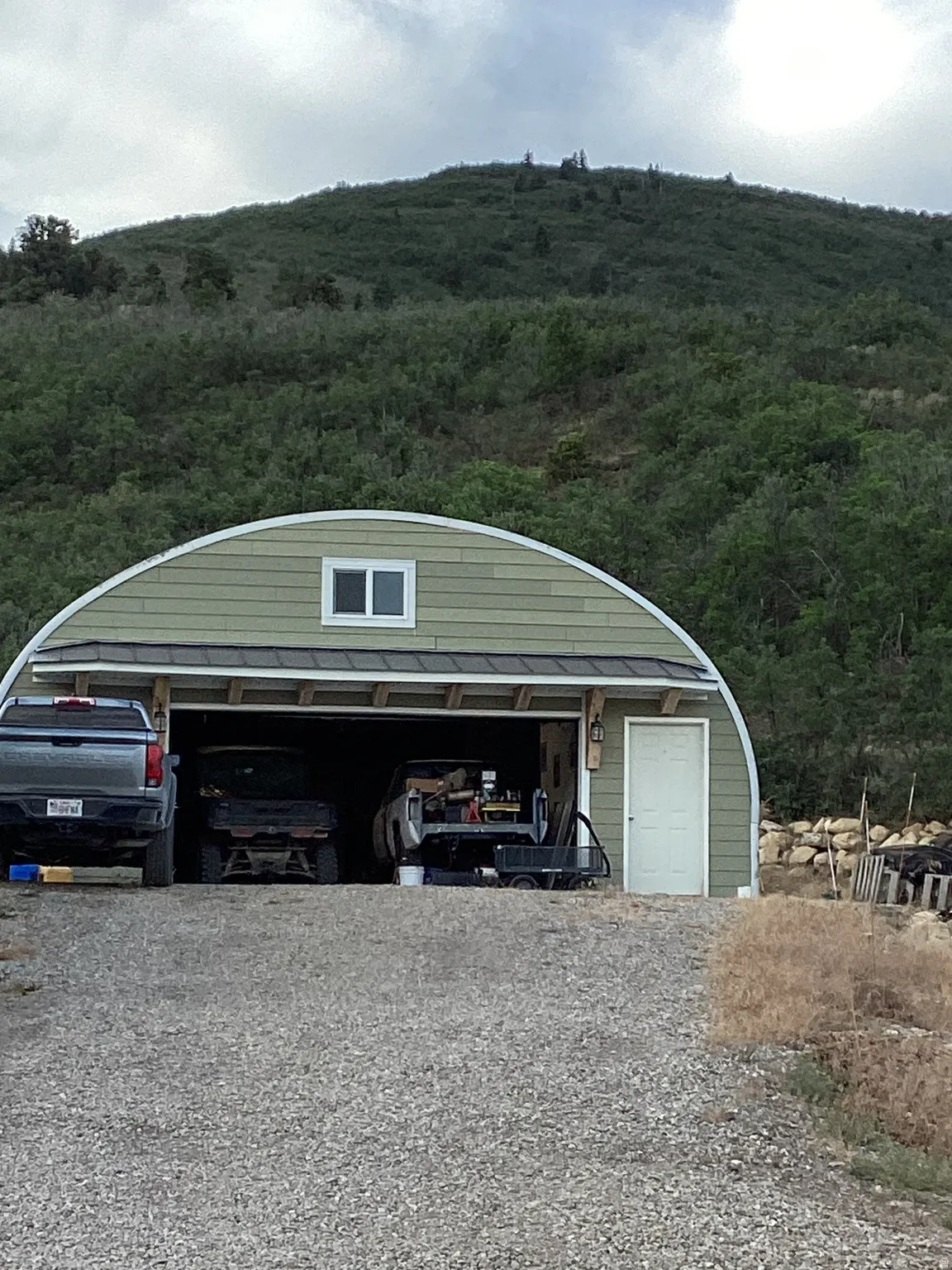 Quonset hut style outbuilding featuring a light green siding exterior