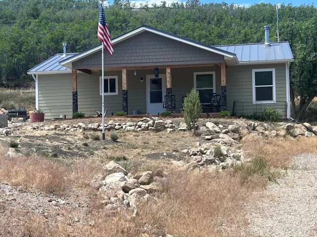 Ranch-style residence featuring a covered porch, stone accents on porch columns, and a light green siding exterior