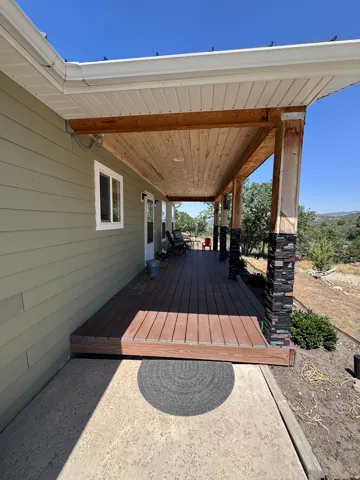 Covered patio featuring a composite deck with clean lines, wooden beam ceiling, and metal support posts