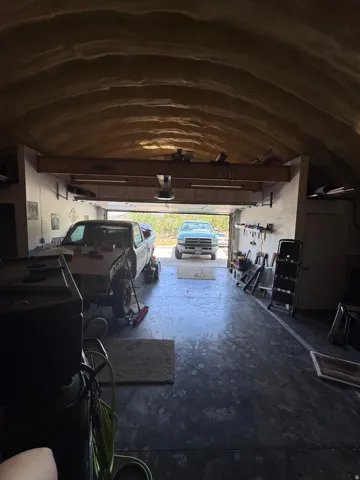 Spacious garage with arched ceiling and concrete flooring, offering ample storage and workspace