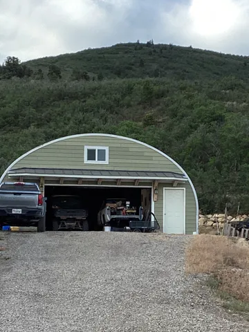 Quonset hut style outbuilding featuring a light green siding exterior