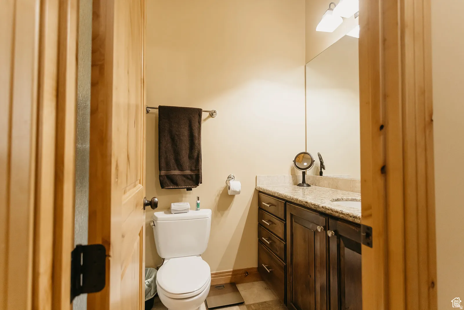 Bathroom featuring a dark wood vanity with a light-toned countertop, a built-in sink, and a large wall-mounted mirror
