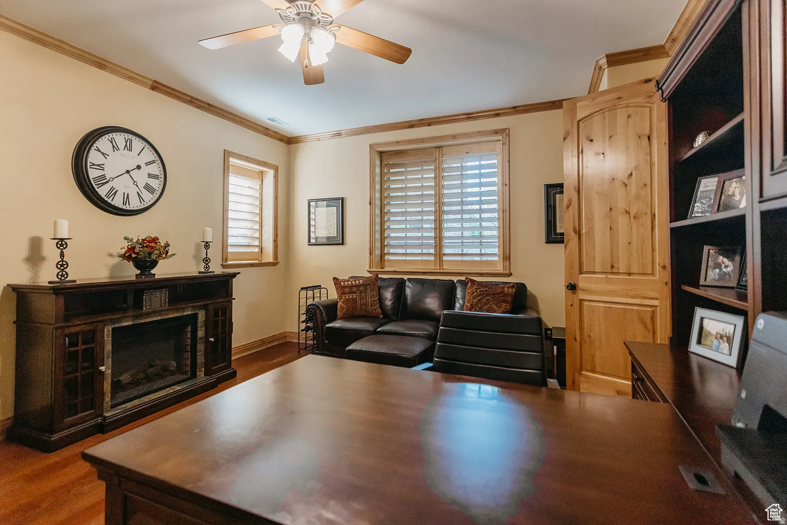 Warmly appointed room featuring wood-finish flooring, wood trim, and a ceiling fan with integrated lighting