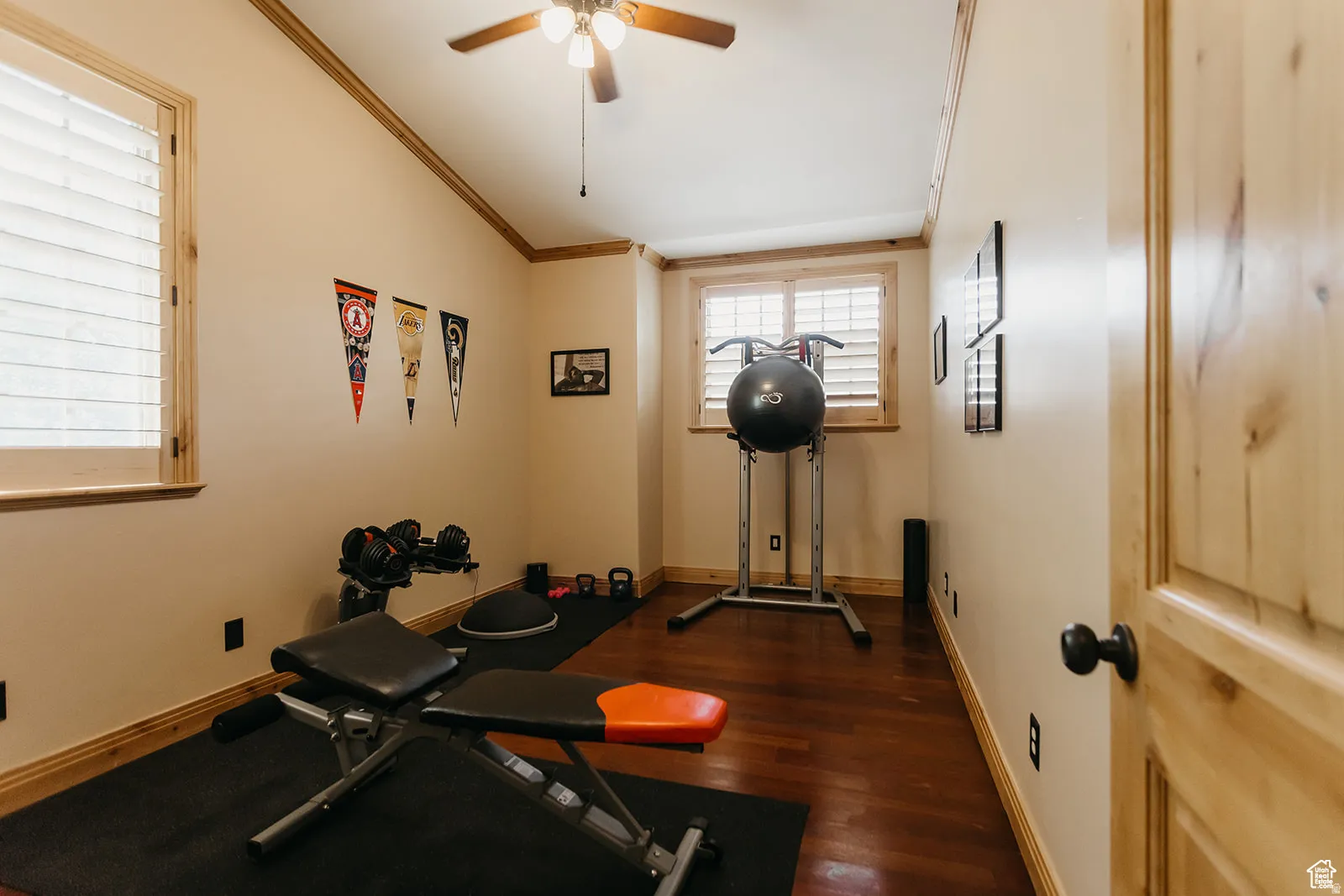 Interior room featuring wood-finish flooring, natural wood window trim, and a ceiling fan with integrated lighting