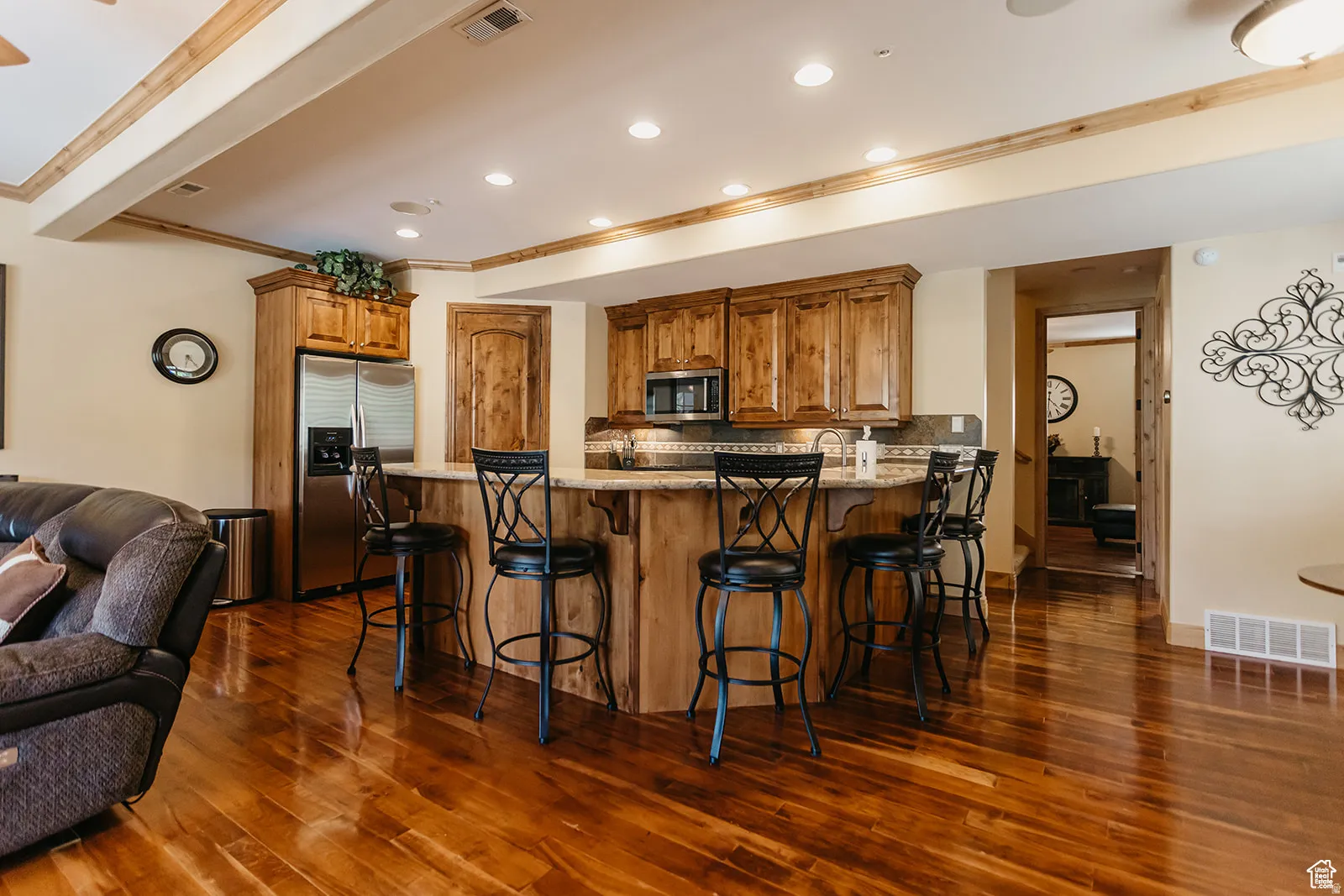 Gourmet kitchen featuring wood-finish cabinetry, stainless steel appliances, and a breakfast bar with stone countertops