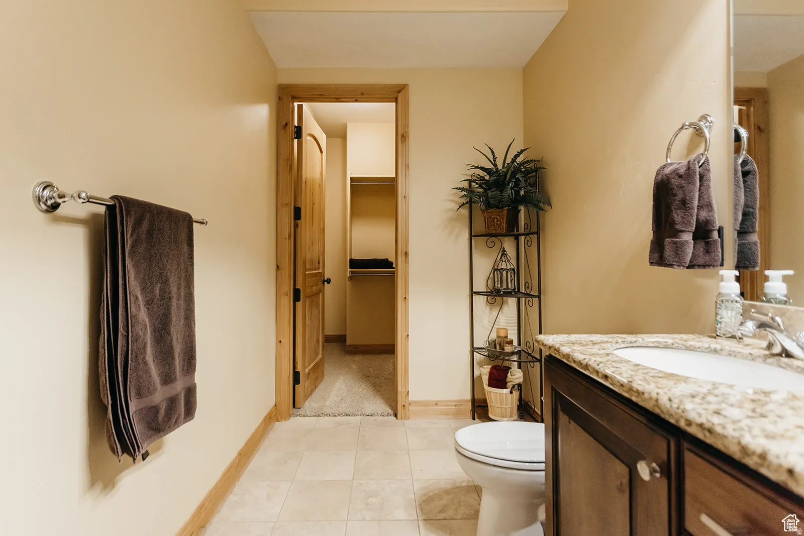 Bathroom featuring tile flooring, a dark wood-finish vanity with a light-toned countertop, and a white porcelain sink