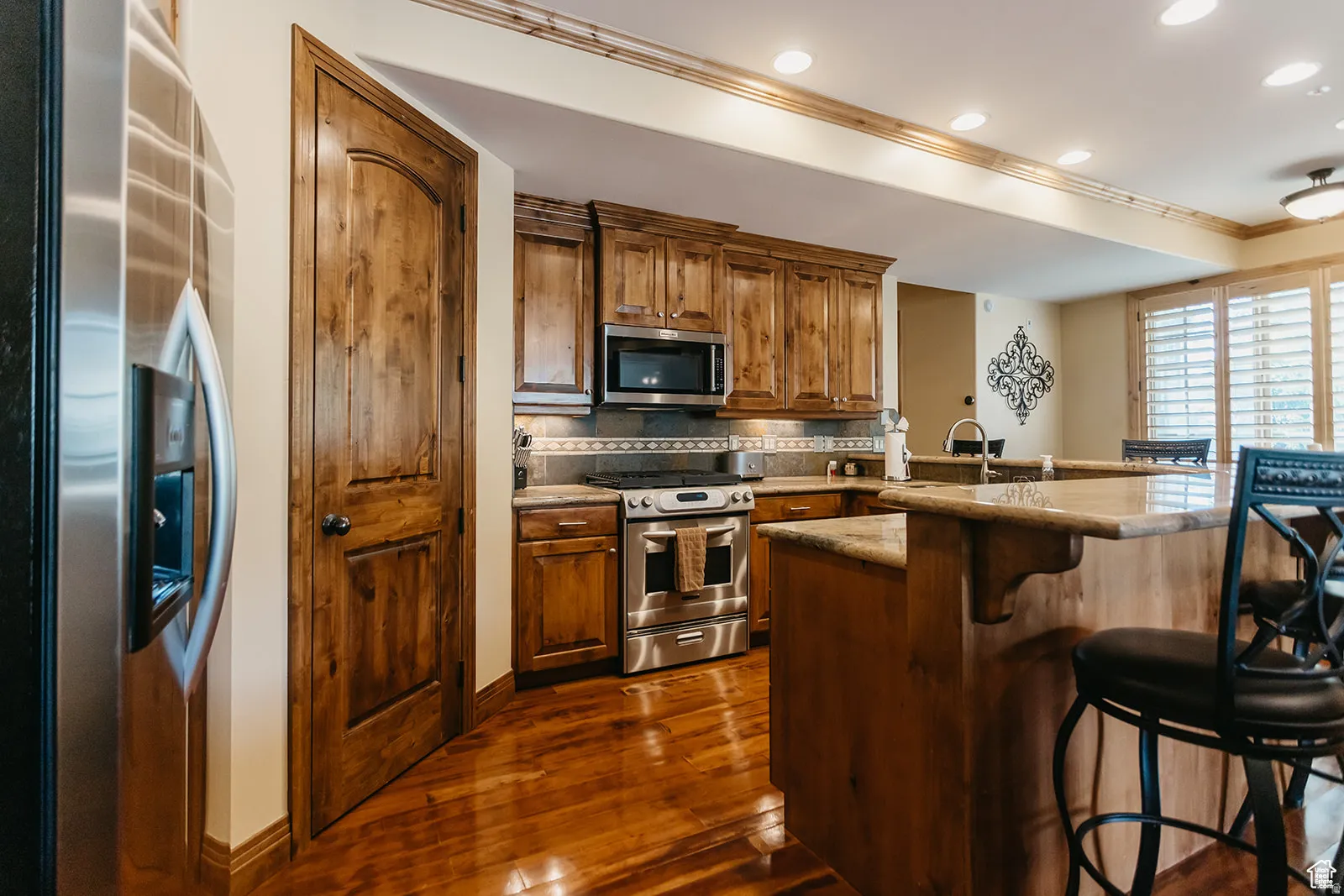 Kitchen featuring wood-finish flooring, recessed lighting, and a dual-level island with seating